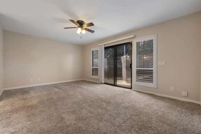 a view of an empty room with chandelier fan and fire place