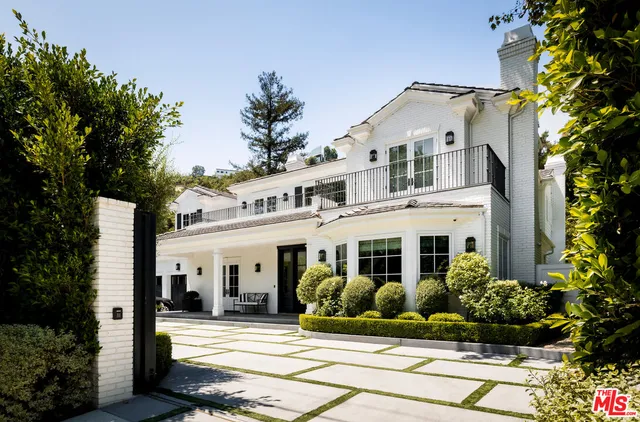 a view of a white house with large windows and a flower garden