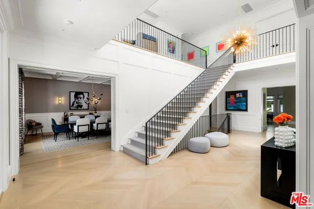 a room with lots of white furniture and a chandelier