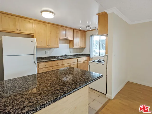 a kitchen with stainless steel appliances granite countertop a refrigerator a stove and a sink