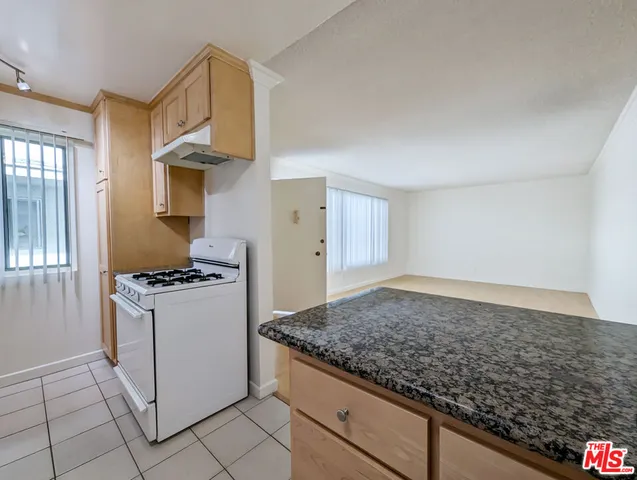 a kitchen with granite countertop a sink stove and cabinets