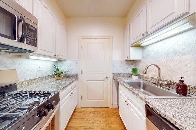 a kitchen with stainless steel appliances granite countertop a sink stove and cabinets