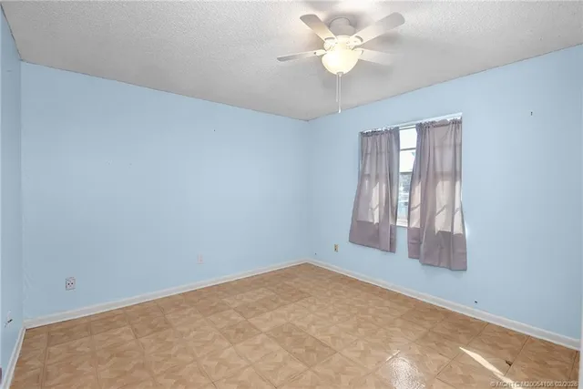 an empty room with windows and ceiling fan