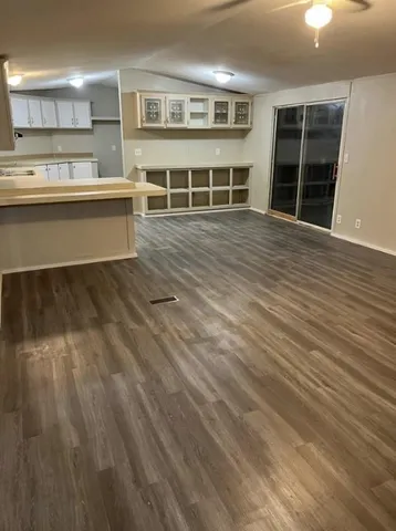 a living room with a wooden floor and kitchen view