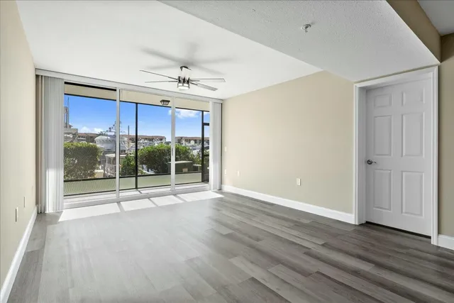 a view of empty room with wooden floor and fan