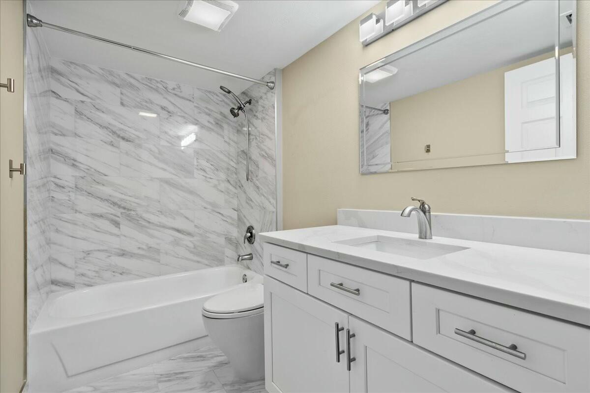2601 Marina Isle Way, Unit 103 Jupiter, FL 33477 - Photo 30 of 56 a bathroom with a granite countertop sink a toilet and shower