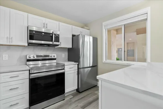 a kitchen with stainless steel appliances white cabinets and a stove top oven