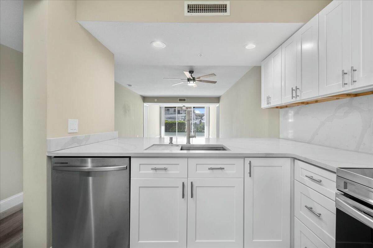 2601 Marina Isle Way, Unit 103 Jupiter, FL 33477 - Photo 4 of 56 a kitchen with granite countertop white cabinets and white appliances