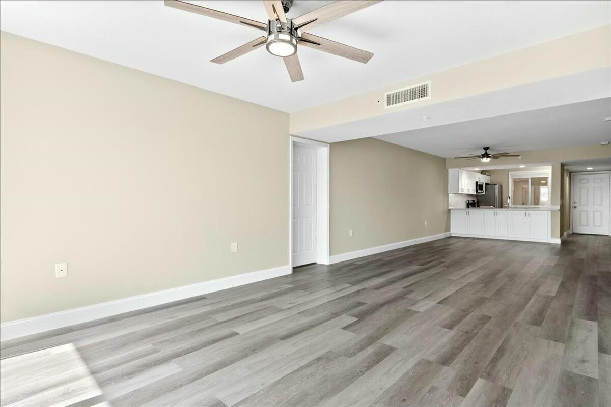 2601 Marina Isle Way, Unit 103 Jupiter, FL 33477 - Photo 8 of 56 an empty room with wooden floor chandelier fan and windows