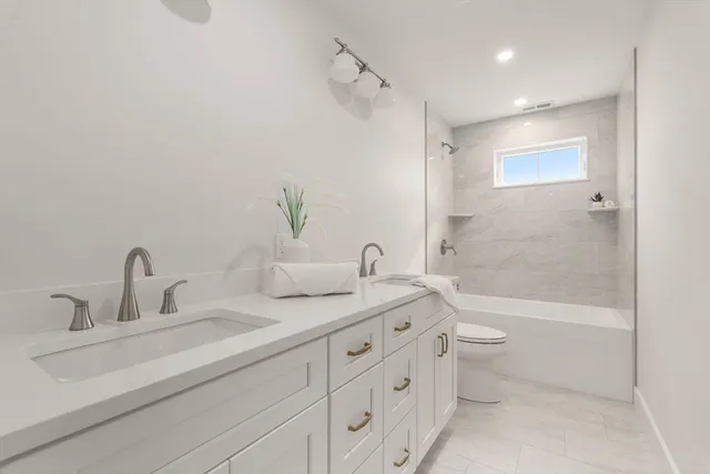 a bathroom with a double vanity sink toilet and shower