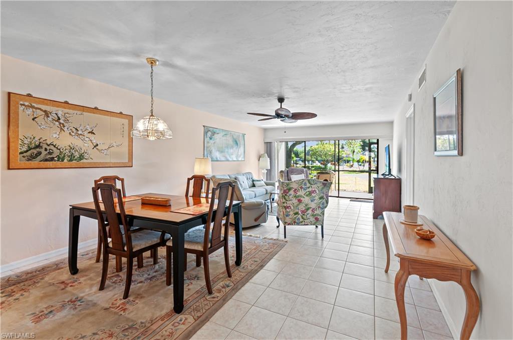 1208 Commonwealth Circle, Unit J103 Naples, FL 34116 - Photo 13 of 31 a view of a dining room and livingroom with furniture wooden floor a rug a painting and a chandelier