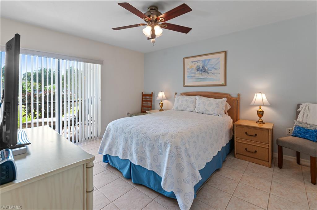 1208 Commonwealth Circle, Unit J103 Naples, FL 34116 - Photo 16 of 31 a bedroom with a bed and a chandelier