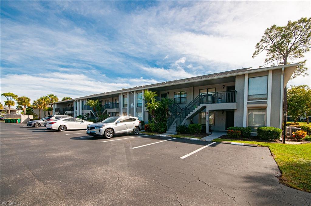 1208 Commonwealth Circle, Unit J103 Naples, FL 34116 - Photo 2 of 33 View of building exterior featuring stairway and uncovered parking