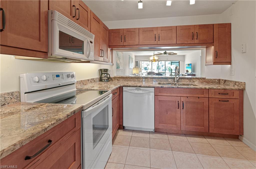 1208 Commonwealth Circle, Unit J103 Naples, FL 34116 - Photo 2 of 31 a kitchen with granite countertop cabinets stainless steel appliances a sink and a counter space