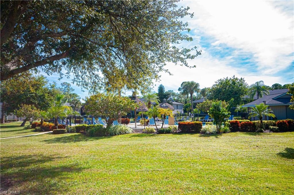 1208 Commonwealth Circle, Unit J103 Naples, FL 34116 - Photo 26 of 31 a view of outdoor space with garden and lots of cars and trees