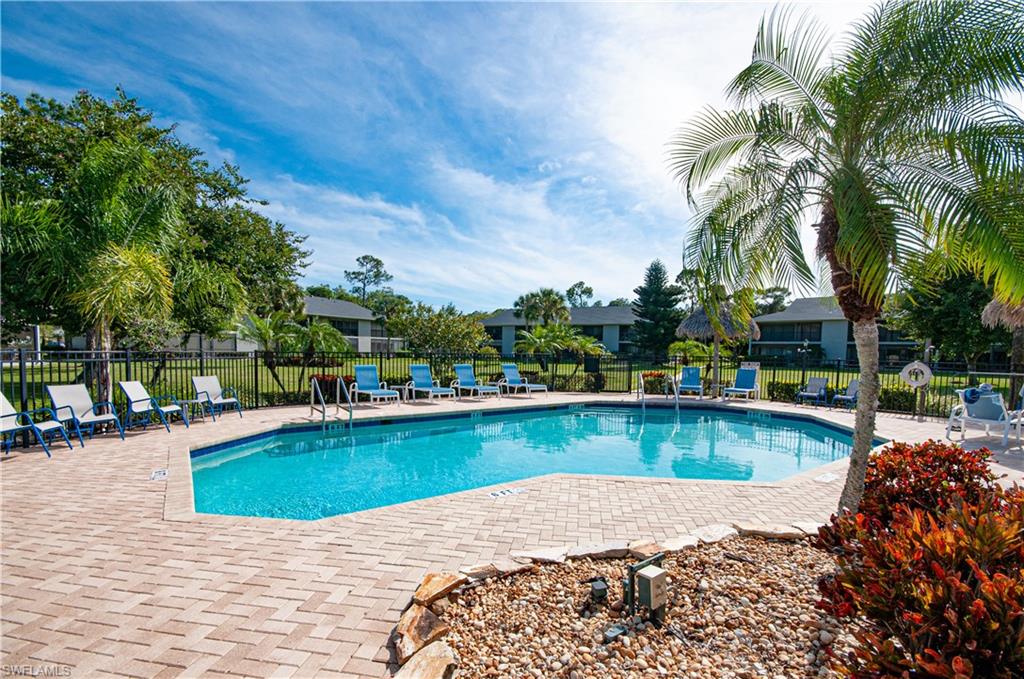 1208 Commonwealth Circle, Unit J103 Naples, FL 34116 - Photo 28 of 31 a view of a swimming pool with a table and chairs in patio