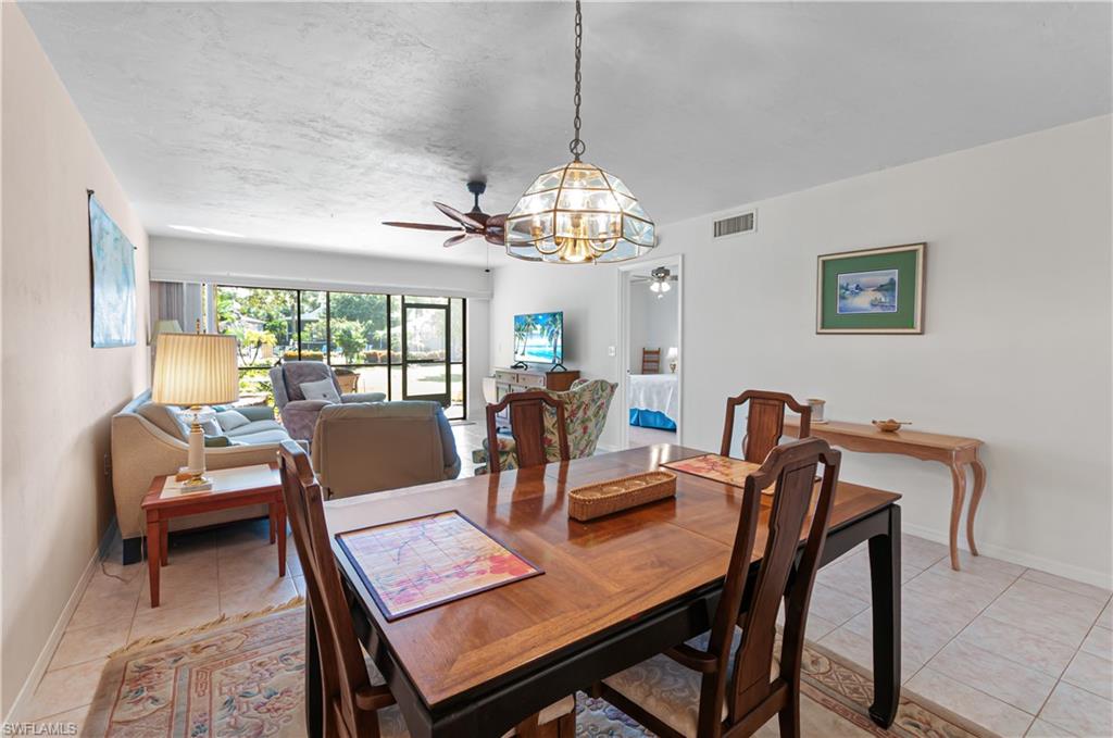 1208 Commonwealth Circle, Unit J103 Naples, FL 34116 - Photo 4 of 31 a view of a dining room with furniture a chandelier and wooden floor