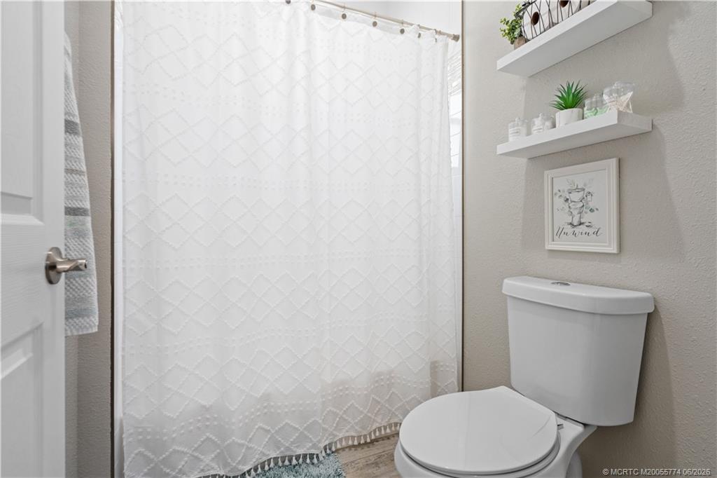 1268 Southeast Kirk Street Stuart, FL 34997 - Photo 43 of 63 a white toilet sitting next to a shower curtain