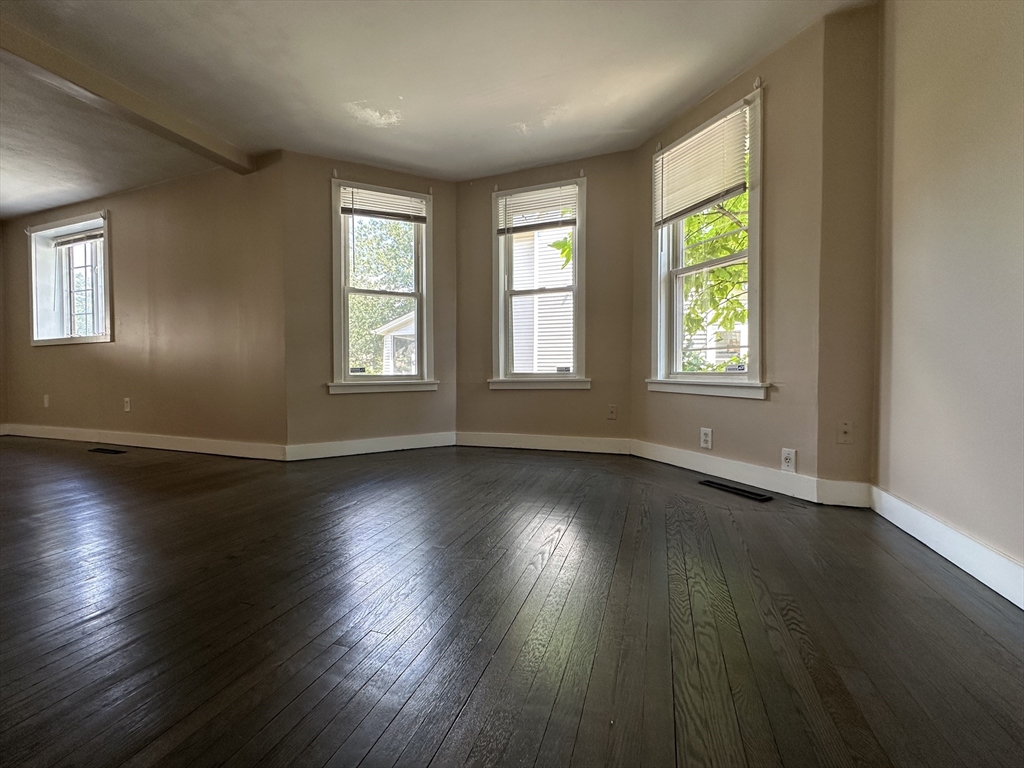 177 Johnson Street Springfield, MA 01108 - Photo 9 of 23 an empty room with wooden floor and windows with curtains view