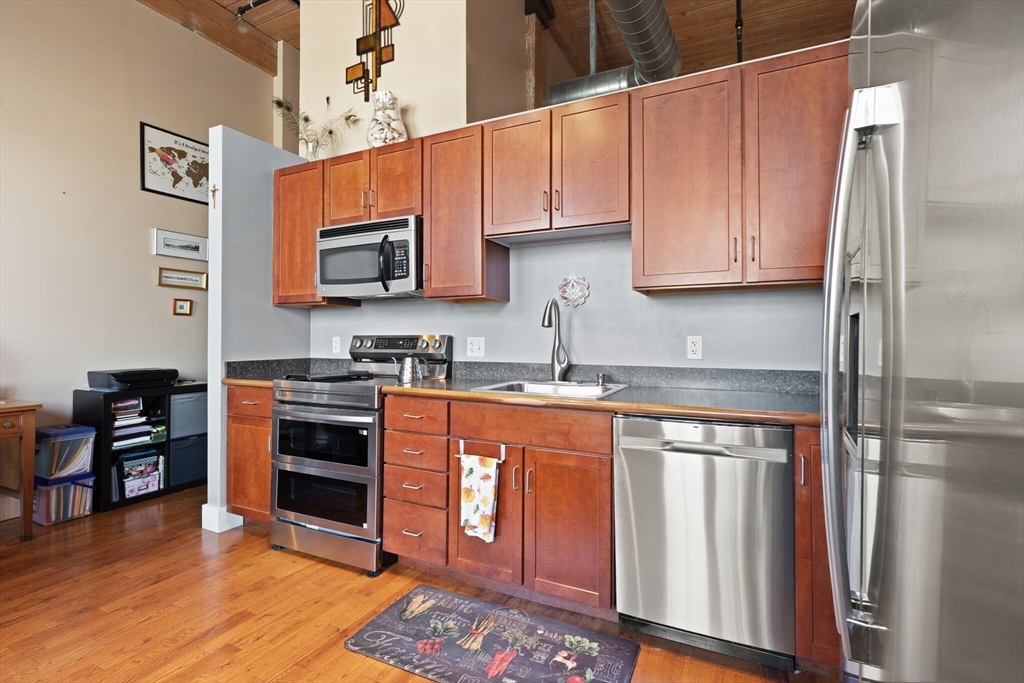99 Allen Street, Unit 205 Woonsocket, RI 02895 - Photo 25 of 37 a kitchen with stainless steel appliances granite countertop a refrigerator and stove top oven