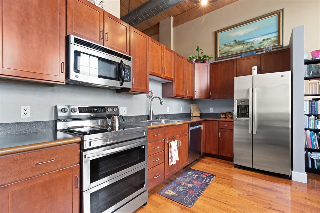 99 Allen Street, Unit 205 Woonsocket, RI 02895 - Photo 26 of 37 a kitchen with stainless steel appliances granite countertop a stove microwave refrigerator and sink