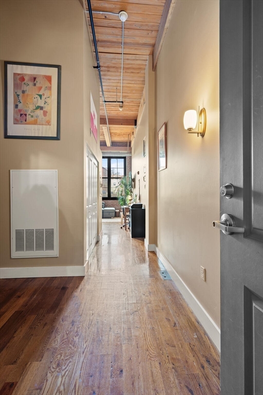 99 Allen Street, Unit 205 Woonsocket, RI 02895 - Photo 8 of 37 a view of a hallway with wooden floor and a living room