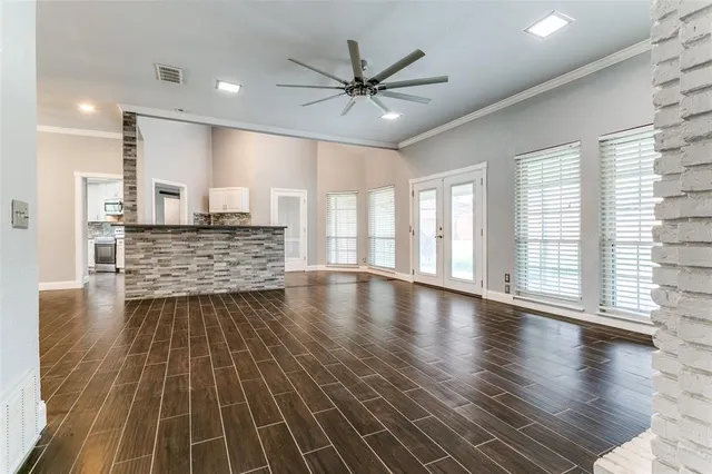 an empty room with wooden floor fan and windows