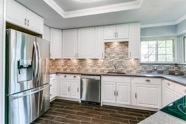 a kitchen with granite countertop a refrigerator sink and cabinets