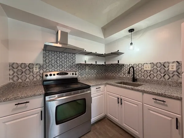 a kitchen with granite countertop white cabinets and white stove
