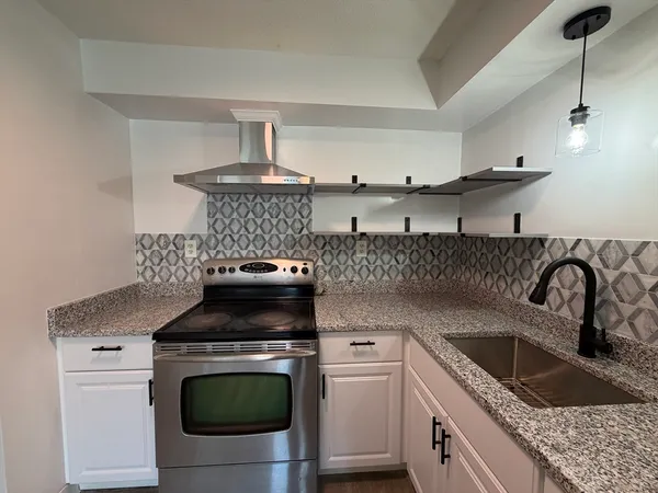 a kitchen with granite countertop a sink a stove and cabinets