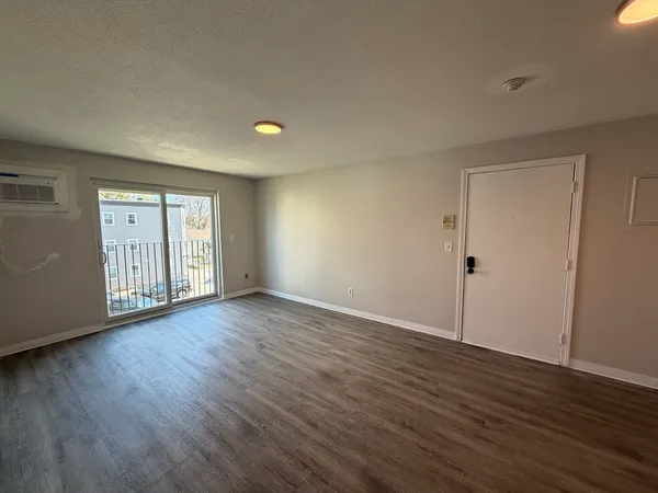 a view of an empty room with wooden floor and windows