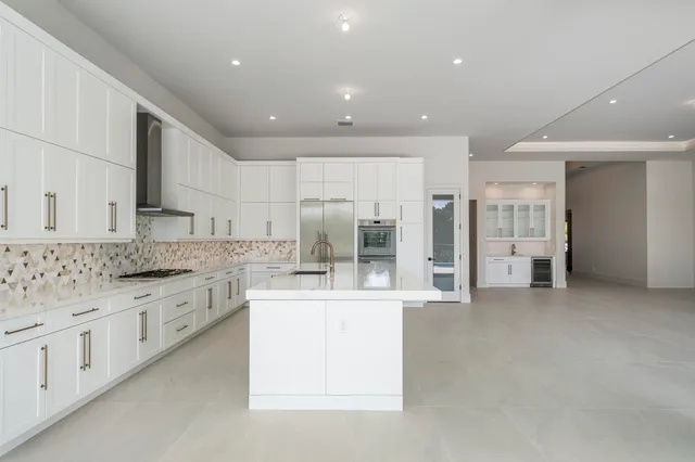 a large white kitchen with a large window and stainless steel appliances