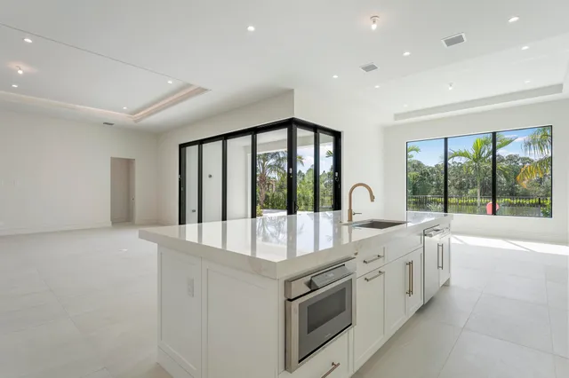 a large white kitchen with granite countertop a large window
