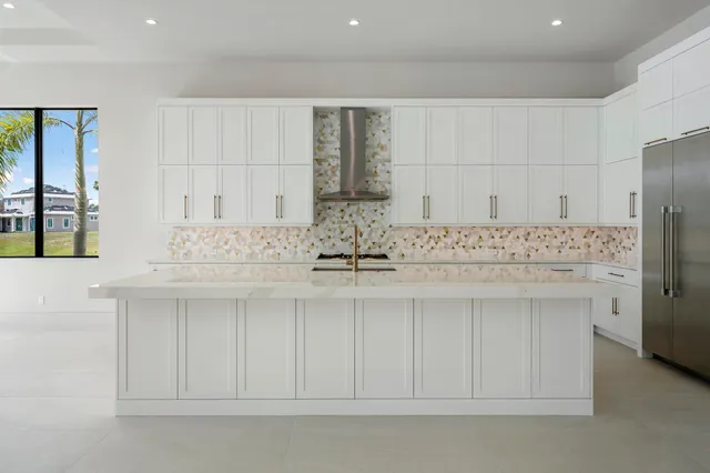a kitchen with kitchen island granite countertop white cabinets and refrigerator