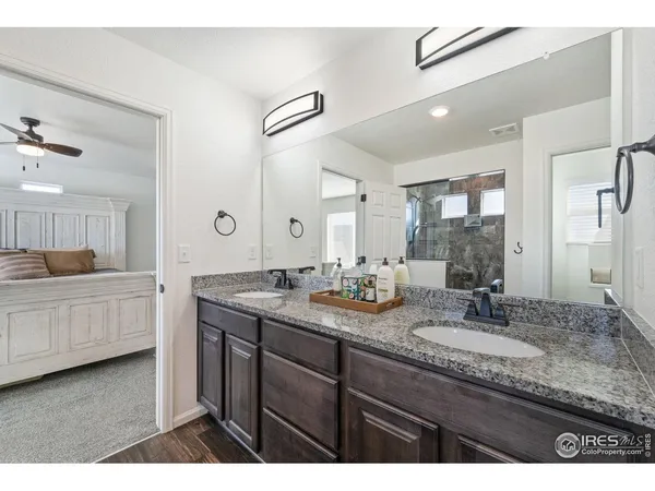 a bathroom with a granite countertop double vanity sink and mirror