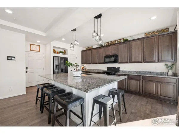 a kitchen with kitchen island granite countertop a table chairs a sink dishwasher refrigerator and microwave