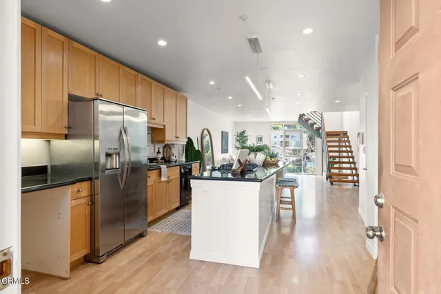 a kitchen with stainless steel appliances kitchen island granite countertop a refrigerator and a stove top oven