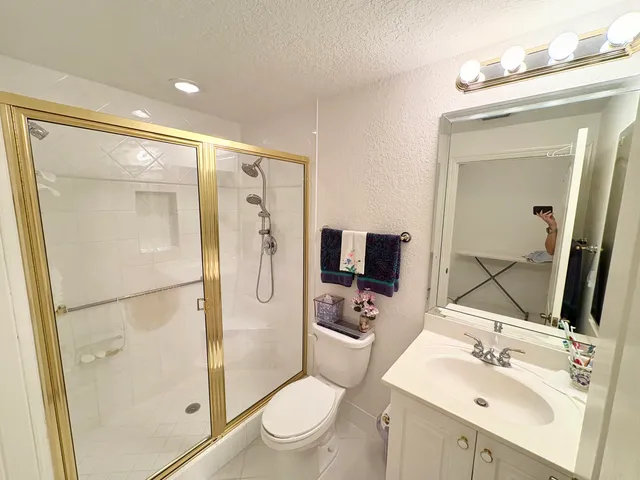 a bathroom with a sink a toilet and shower a mirror