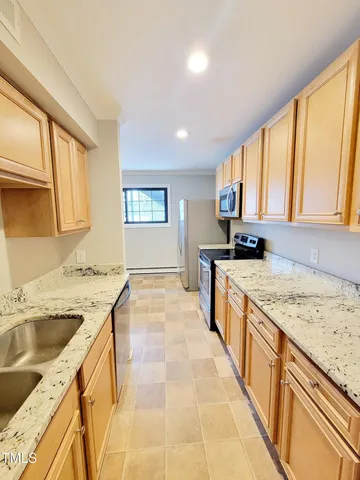 a large kitchen with a stove top oven a sink a counter space and cabinets