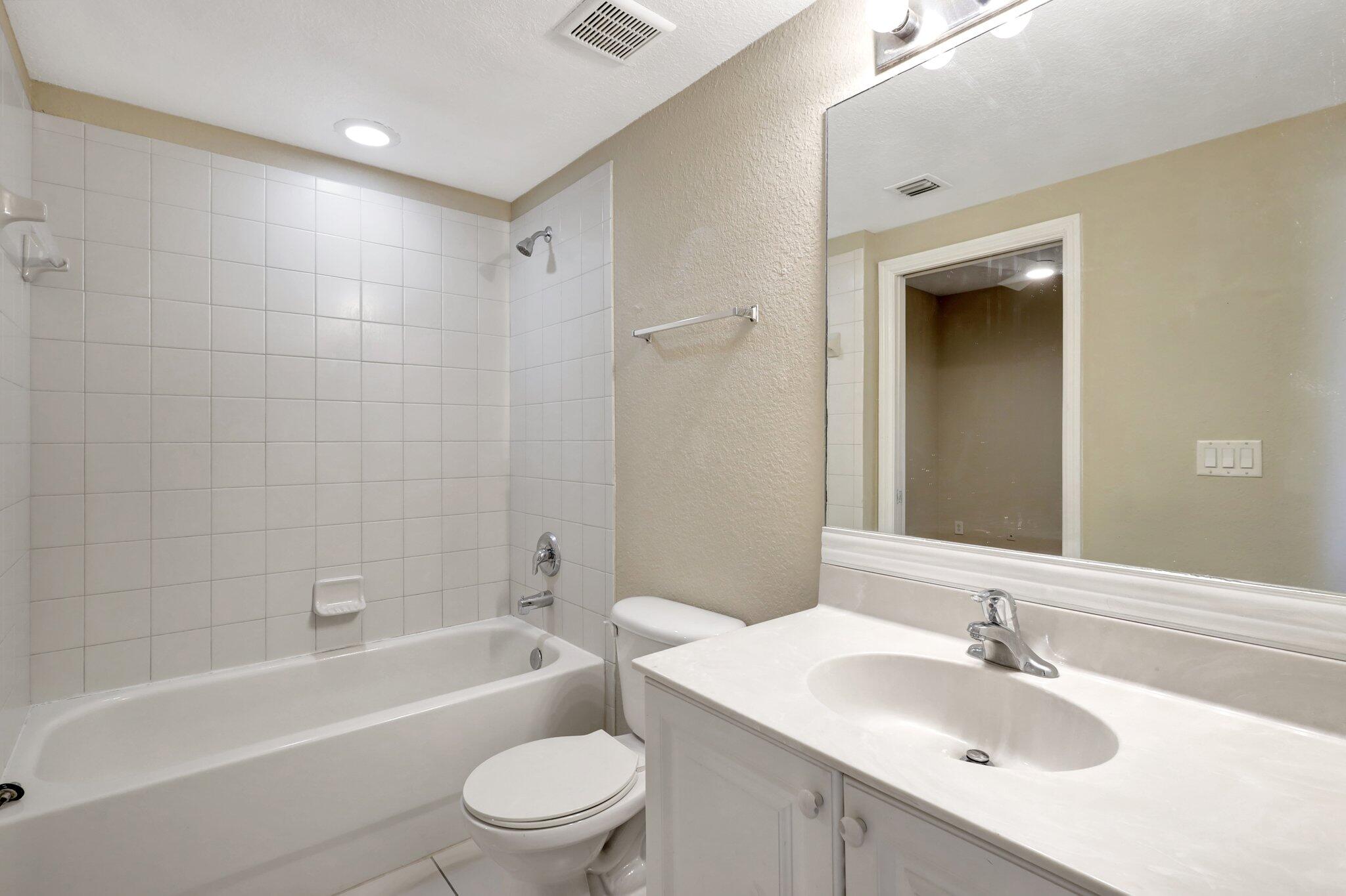 1964 Freeport Drive, Unit 1964 Riviera Beach, FL 33404 - Photo 11 of 20 a bathroom with a bathtub shower sink vanity mirror and toilet