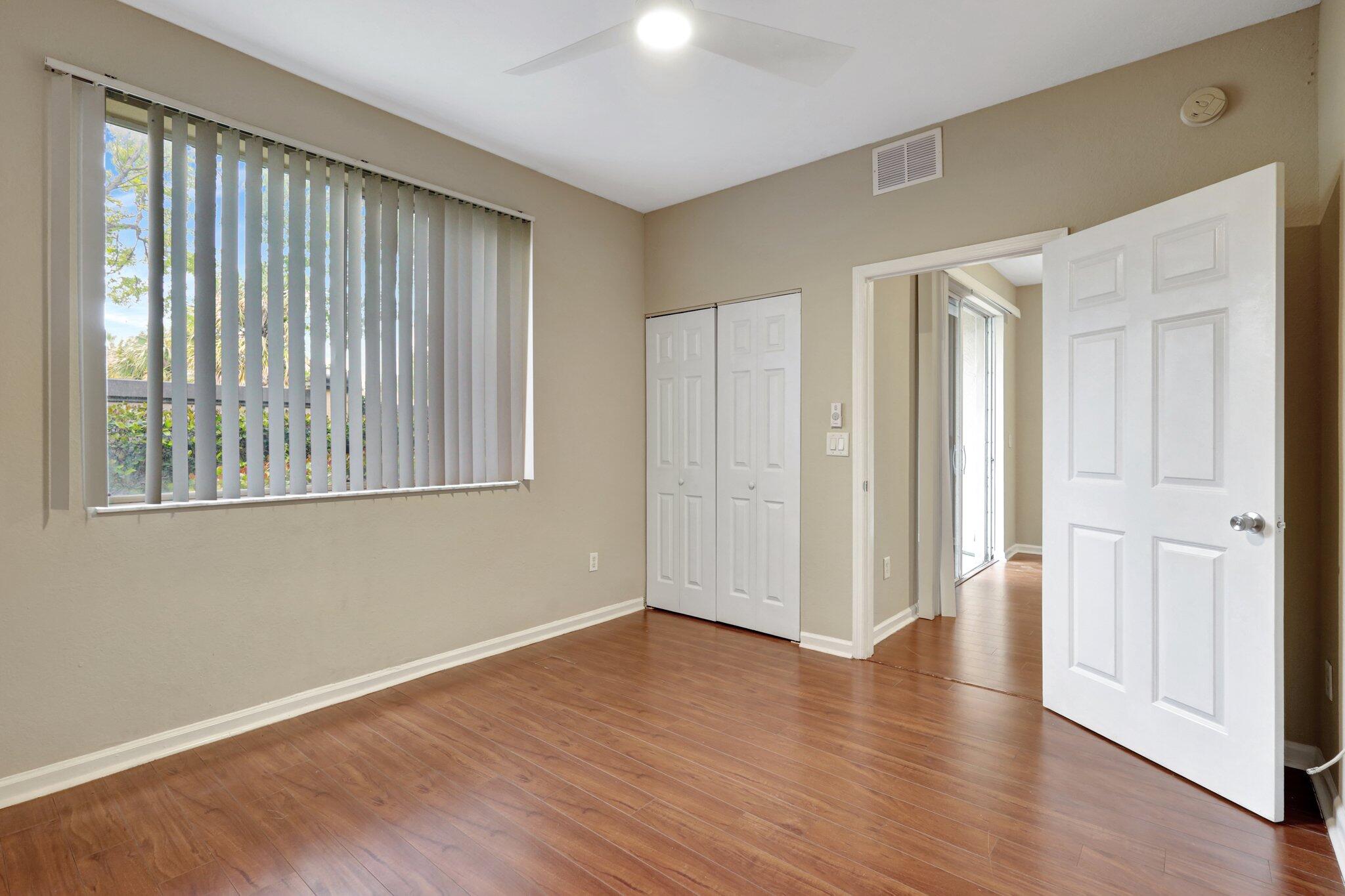 1964 Freeport Drive, Unit 1964 Riviera Beach, FL 33404 - Photo 17 of 20 a view of an empty room with wooden floor and a window