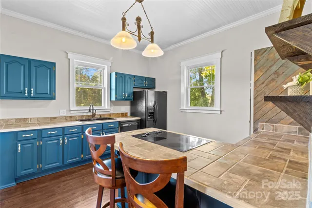 a kitchen with stainless steel appliances granite countertop a sink a stove a refrigerator a dining table and chairs with wooden floor