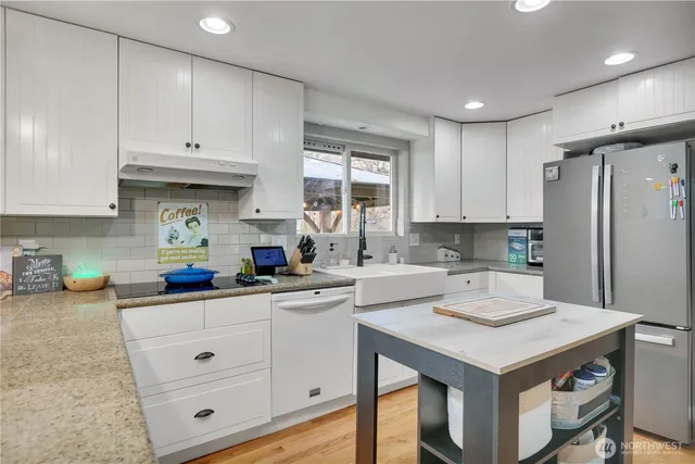 a kitchen with a sink dishwasher a stove and white cabinets with wooden floor