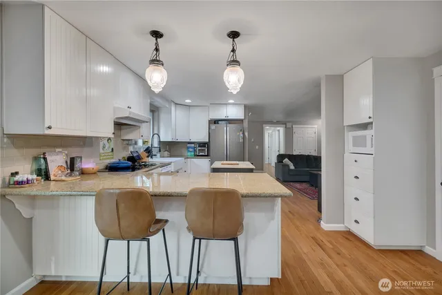 a kitchen with stainless steel appliances granite countertop a refrigerator a stove a sink dishwasher a dining table and chairs with wooden floor