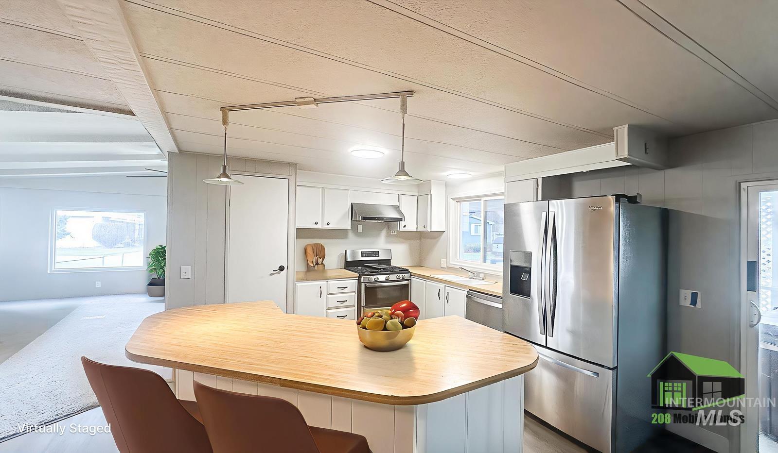 1200 Artesian Road Eagle, ID 83616 - Photo 8 of 18 Kitchen with light countertops, stainless steel appliances, white cabinets, hanging light fixtures, and a kitchen island