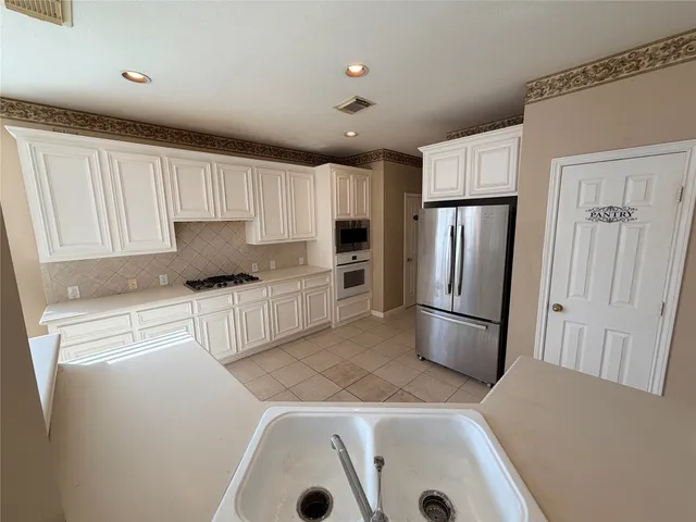 a kitchen with a refrigerator a stove and white cabinets