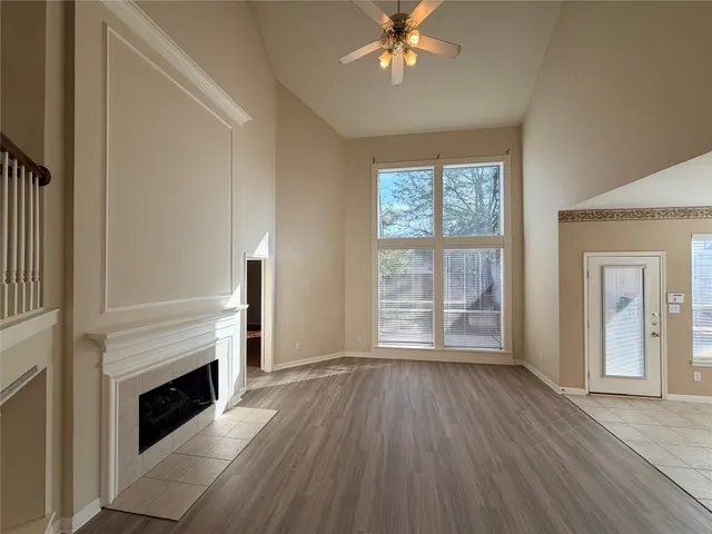 a view of an empty room with wooden floor fireplace and a window