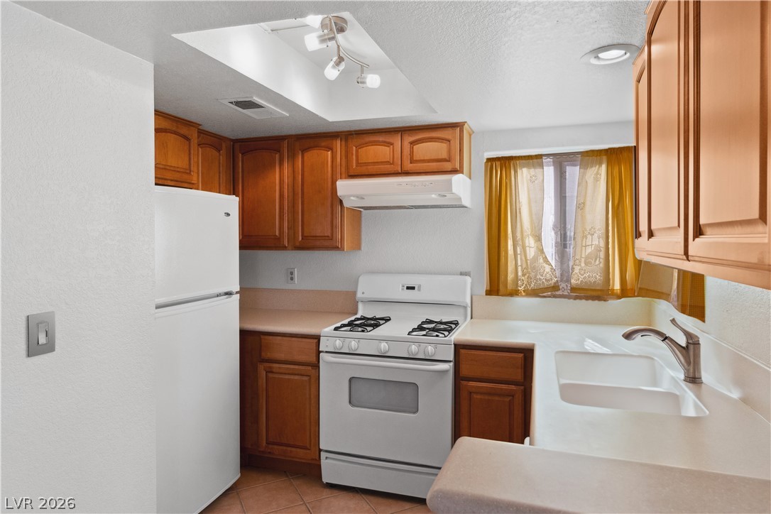 2146 High Dunes Lane Laughlin, NV 89029 - Photo 13 of 64 Kitchen with white appliances, a textured ceiling, under cabinet range hood, white countertops, and a sink