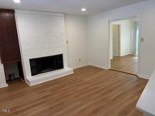 an empty room with wooden floor and fireplace