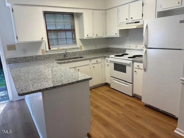 a kitchen with granite countertop a sink stove and refrigerator